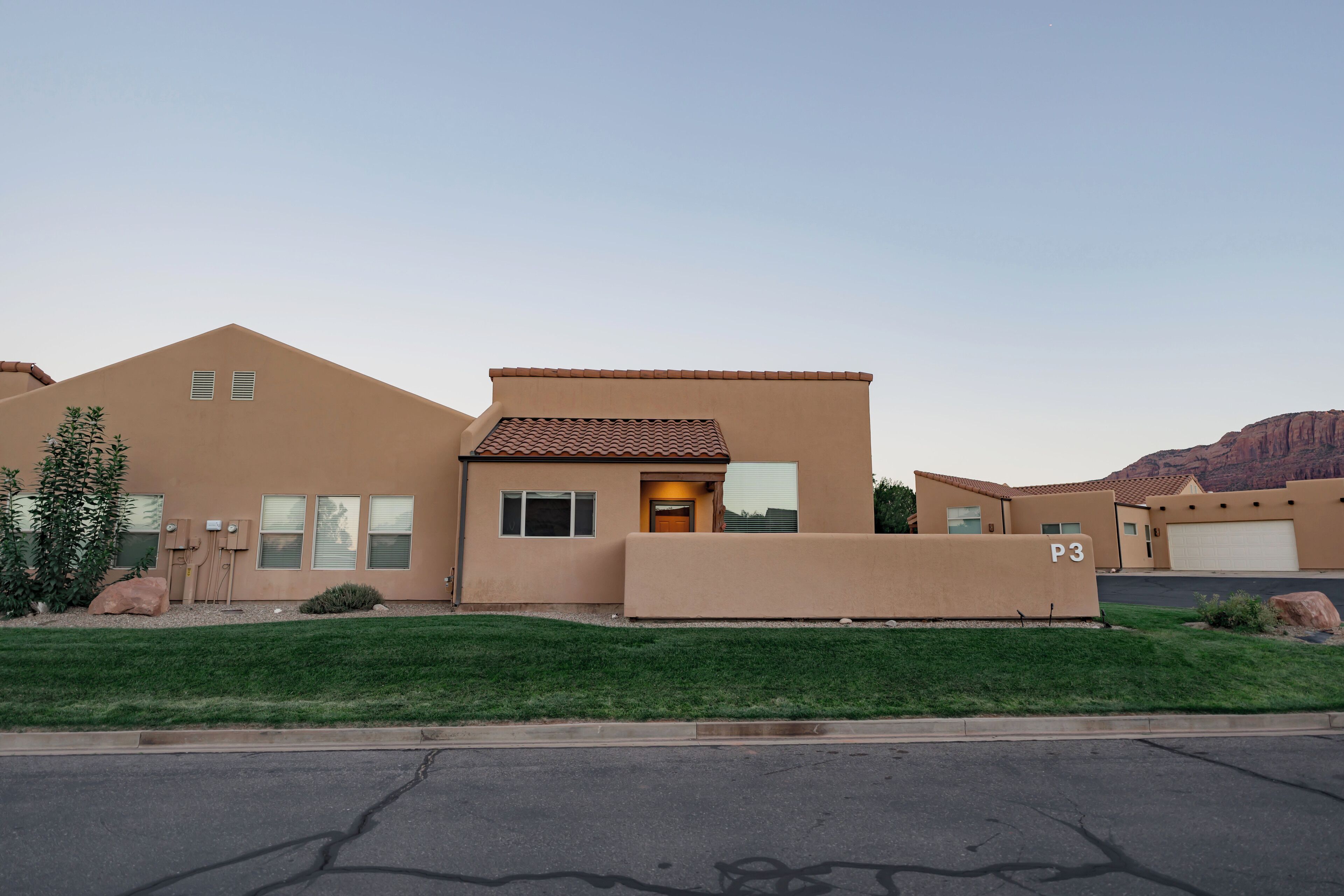 A modern two-story house with a flat roof, a garage, and a well-maintained lawn.