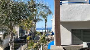 A terrace with a view of the ocean, palm trees, and a pool area. - ☀️PERFECT LOCATION, SPACIOUS and affordable! SOUTH MISSION BEACH Steps to Ocean! (San Diego)
