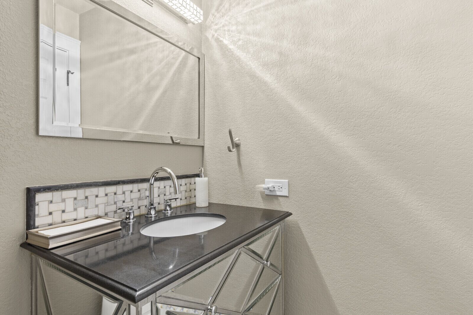 Een badkamer met een wastafel, spiegel en handdoekdispenser.