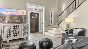 Un salon spacieux avec une grande télévision, un escalier et un canapé en cuir.