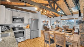 Une cuisine spacieuse dotée d’appareils électroménagers modernes, un coin repas avec des meubles en bois et un mur décoratif en pierre.