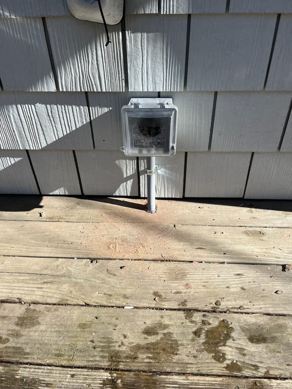 Una caja de servicios instalada en una cubierta de madera, con una pared revestida de madera al fondo.