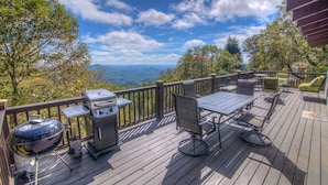 Une terrasse dotée d’un barbecue, d’une table et de chaises, offrant une vue sur un paysage montagneux.