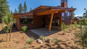 Een modern huis met een houten gevel, grote ramen en een stenen fundering.