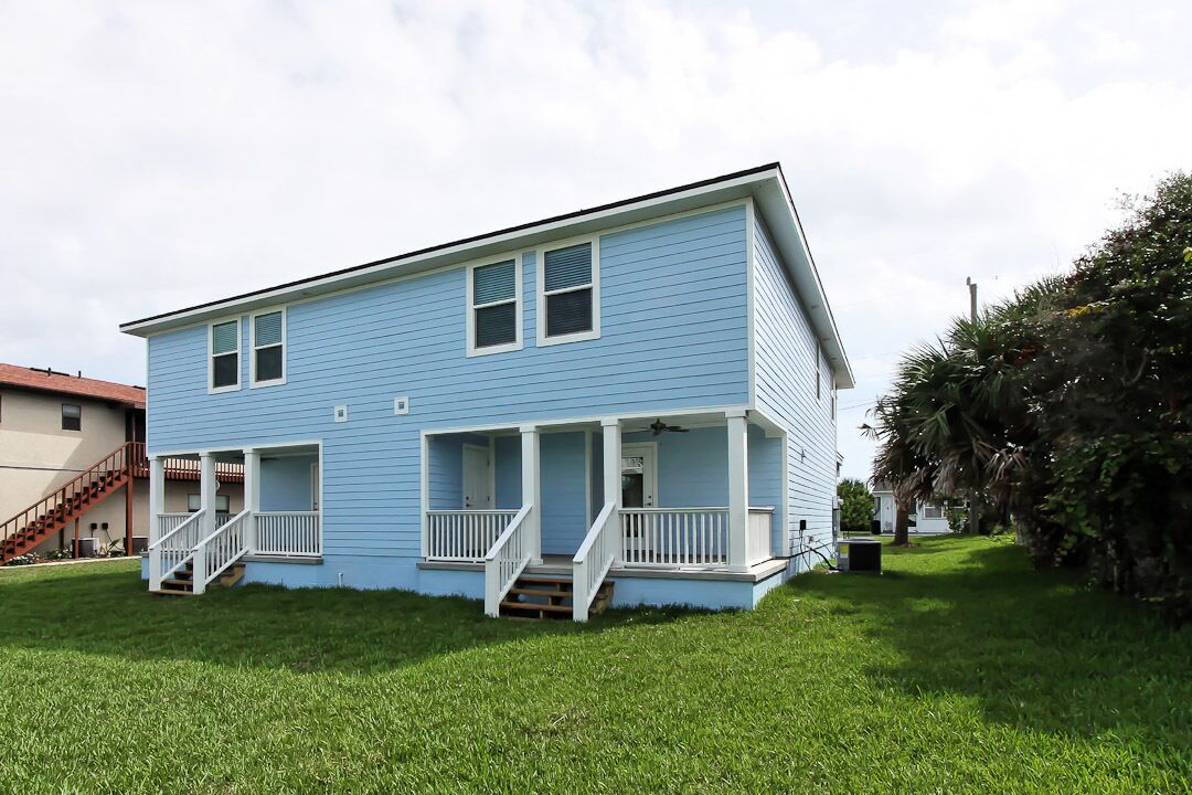 A two-story house with a porch and a staircase leading to the entrance.