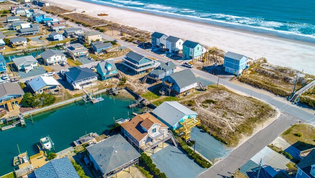 Vista aérea de una zona residencial costera con casas, un puerto deportivo y una playa.