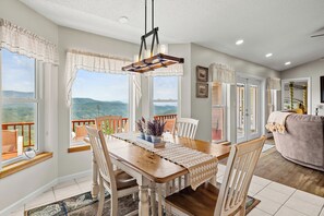 Un comedor con una mesa de madera, sillas y vistas a las montañas.