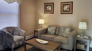 A living room with a sofa, armchair, coffee table, lamps, and framed pictures on the wall. - Renovated and walking distance to Downtown  (Beaufort)