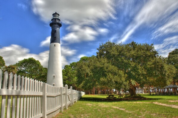 A lighthouse with a white and black exterior, surrounded by a white picket fence, trees, and picnic areas. - Renovated and walking distance to Downtown (Beaufort)