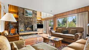A cozy living room with a fireplace, leather sofas, wooden flooring, and a stone wall. - RMR: Wind River 10 Condo in Teton Village (Teton Village)