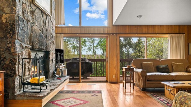 A spacious living room with a fireplace, a sofa, a coffee table, and a view of the outdoors. - RMR: Wind River 10 Condo in Teton Village (Teton Village)