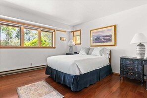 Une chambre à coucher comprenant un lit, une table de chevet, une lampe, une commode et deux tableaux encadrés accrochés au mur.