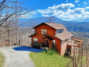 A two-story wooden cabin with a front porch, a deck, and a view of mountains in the background. - Her Majesty's Way, Awesome Mtn Views, FREE tickets each paid day, Hot TUB, WIFI (Gatlinburg)