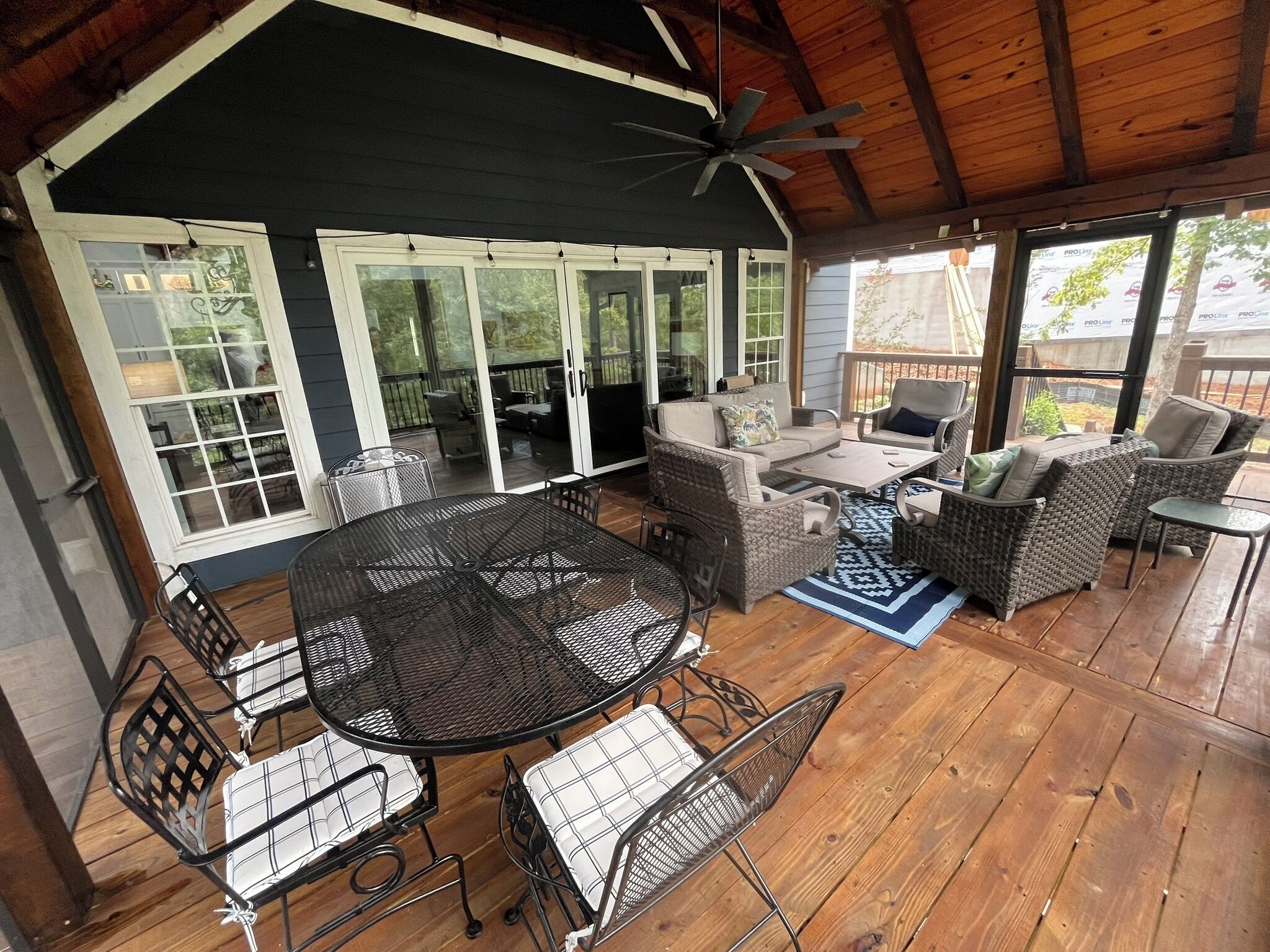 A covered outdoor patio with a round table and chairs, a ceiling fan, and a view of the backyard.
