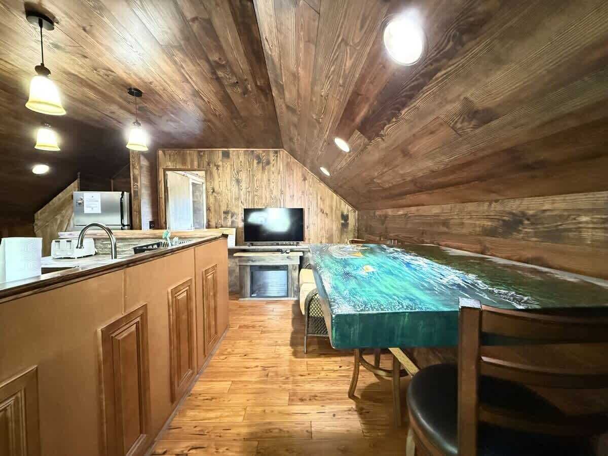 Una cocina rústica con paredes de madera, una mesa de comedor y un televisor.