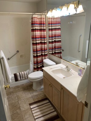 A bathroom with a shower, toilet, sink, and a mirror. - Las Palmas resort ground floor 3 bedroom condo large couch seating hottubs pools (St George)