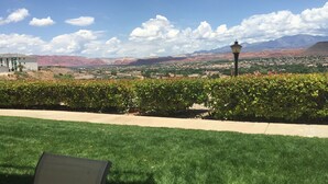 A well-maintained lawn with a clear view of a distant town and mountains. - Las Palmas resort ground floor 3 bedroom condo large couch seating hottubs pools (St George)