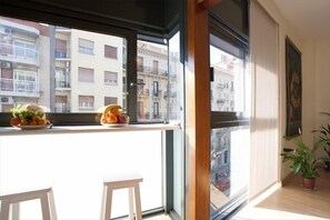 Un balcón con vistas a la ciudad, una mesa con fruta y una planta en maceta.