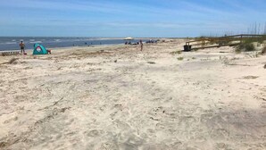 En strand med et telt og en træbro.