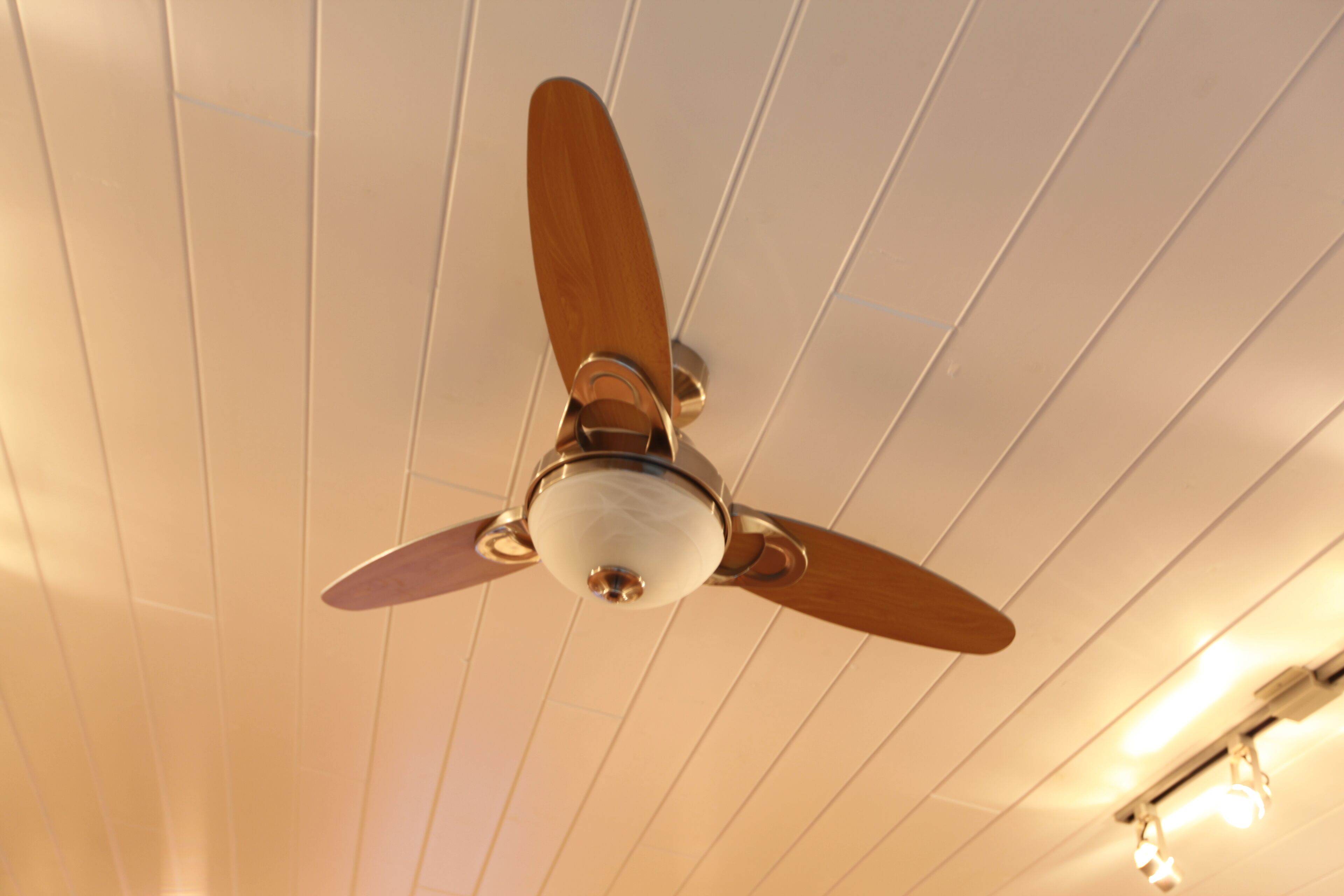 A ceiling fan with wooden blades and a central light fixture.
