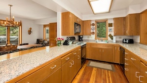 A modern kitchen with wooden cabinets, granite countertops, and a skylight.