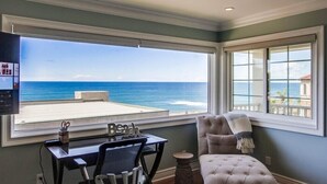 Una habitación con vistas al océano, un escritorio con una silla y un ventanal grande.