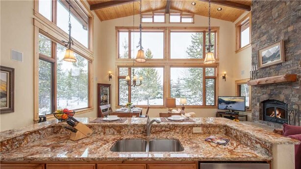 A spacious kitchen with granite countertops, wooden cabinets, and a stone fireplace.