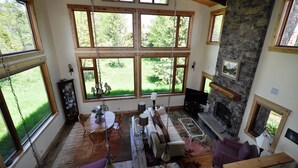 A spacious living room with large windows, a stone fireplace, and a cozy seating area.