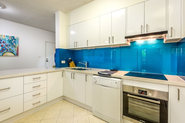 A modern kitchen with white cabinets, a blue backsplash, and a Bosch oven.
