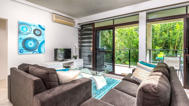 A modern living room with a sofa set, a glass coffee table, and a TV. - Tranquility Chill at Palm Cove (Palm Cove)