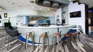 Eine moderne Bar mit einer gebogenen Theke, mehreren Barhocker und hängenden Pendelleuchten.