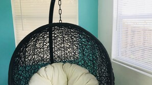 A black woven hanging chair with a white cushion and a colorful pillow. - Cozy 4 Bdrm 2Bath Home close to Design District, Wynwood #ArtBasel #MiamiBeach (Miami)