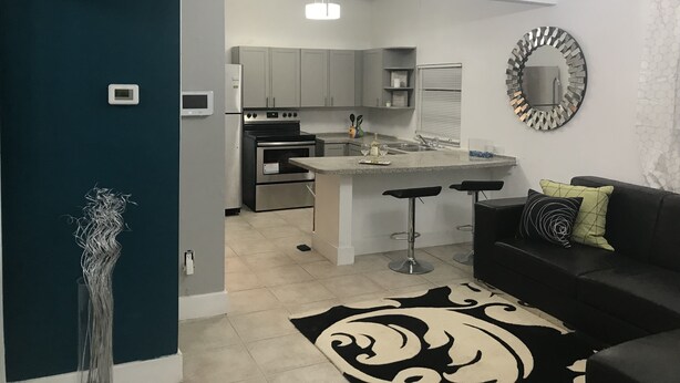 A modern kitchen with a central island, bar stools, and a black and white patterned rug. - Cozy 4 Bdrm 2Bath Home close to Design District, Wynwood #ArtBasel #MiamiBeach (Miami)