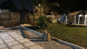 A paved pathway leading to a grassy area with a palm tree and a fence. - Cozy 4 Bdrm 2Bath Home close to Design District, Wynwood #ArtBasel #MiamiBeach (Miami)
