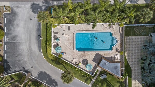 An aerial view of a resort with a swimming pool, sun loungers, and a parking area. - Walk to the #1 Beach in America, Offers Heated community Pool, Free Wi-Fi (Siesta Key)