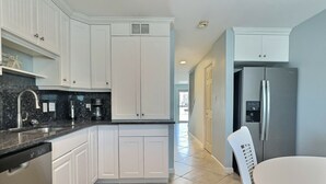 A modern kitchen with white cabinetry, a stainless steel refrigerator, and a dishwasher. - Walk to the #1 Beach in America, Offers Heated community Pool, Free Wi-Fi (Siesta Key)