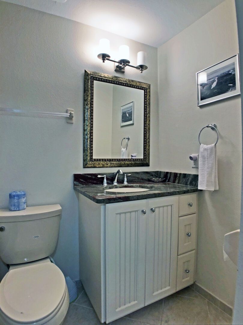 Un baño con inodoro, lavabo, tocador y espejo.