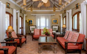 A room with a glass-top coffee table, two sofas, a floor lamp, and a painting on the wall. - Reefside Villa: Full AC! Pool! Private sandy beach! (St John)