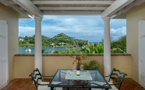 A glass table with a bottle and glasses, overlooking a body of water and greenery. - Reefside Villa: Full AC! Pool! Private sandy beach! (St John)