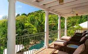 A covered outdoor area with a pool, wicker furniture, and a view of lush greenery. - Reefside Villa: Full AC! Pool! Private sandy beach! (St John)