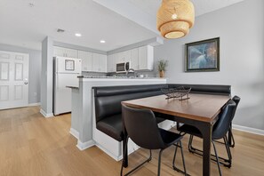 A modern kitchen with white cabinets, a black leather bench, and a wooden dining table with four chairs.