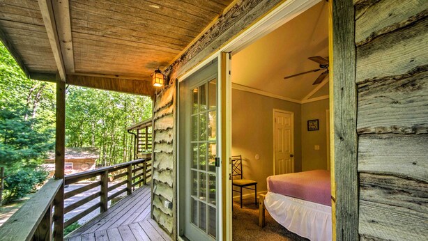 A wooden deck with a glass door leading to a bedroom with a bed and a chair. - Forest Views! ‘The Woodshop’ Robbinsville Cabin (Robbinsville)