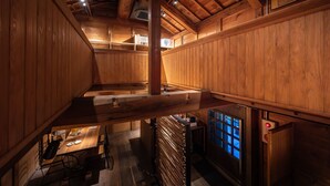 A wooden interior with a dining area, a staircase, and a view of the outside through a window. - Machiya Hotel Oyado Baison (Mino)