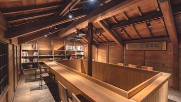 A wooden interior with bookshelves, a long wooden counter, and a sign with Japanese characters.