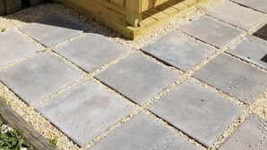 Une clôture en bois avec un portail, une décoration en forme de ballon aux couleurs vives et un chemin pavé.