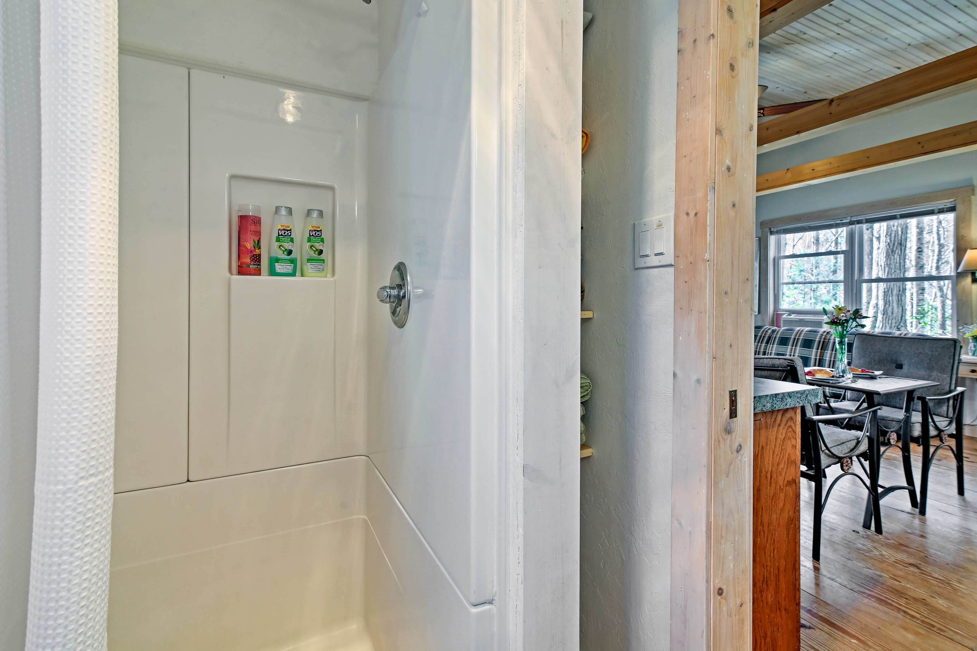 A bathroom with white tiles, a shower curtain, and toiletries on the wall.