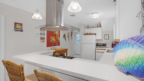 A modern kitchen with white cabinetry, a central island, and pendant lighting. - ABOUT TIME at The Truman Annex in Key West (Key West)