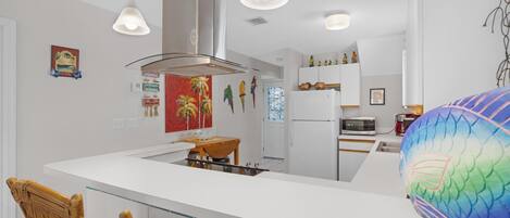 A modern kitchen with white cabinetry, a central island, and pendant lighting.