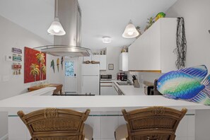Uma cozinha moderna com armários brancos, uma ilha central e uma área de refeições com cadeiras de madeira.