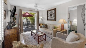 A living room with a sofa, armchair, coffee table, and a television mounted on the wall. - ABOUT TIME at The Truman Annex in Key West (Key West)